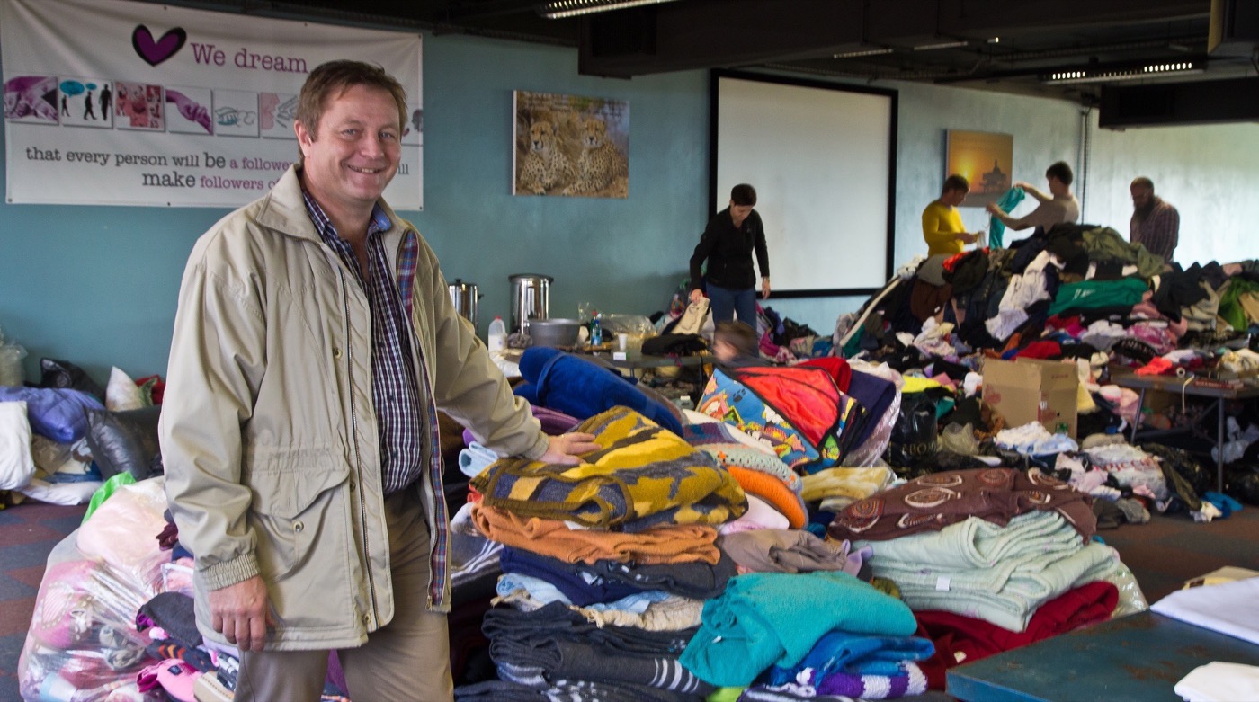 Pieter Breytenbach, bestuurder van die NG gemeente Moreletapark, by ʼn hoop komberse wat ingekom het na die brand in die area langs die kerkgebou. Agter sorteer mense van die klere uit wat ingestroom het. Die foto is geneem nadat die eerste klomp klere en komberse reeds uitgedeel is. Foto: Neels Jackson